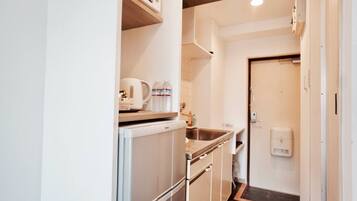 A compact kitchenette with a microwave, kettle, and sink.