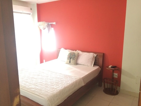 A bedroom with a bed, a bedside table, and a chair.