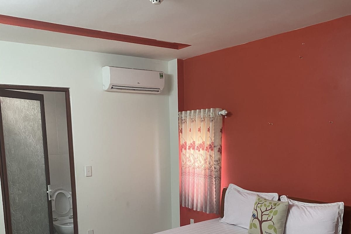 Un dormitorio con cama, aire acondicionado, ducha y retrete.