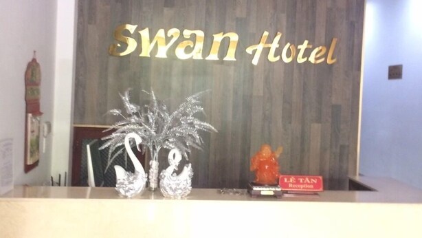 Un comptoir d’accueil avec un panneau en bois en arrière-plan et l’inscription « Swan Hotel » en lettres dorées.