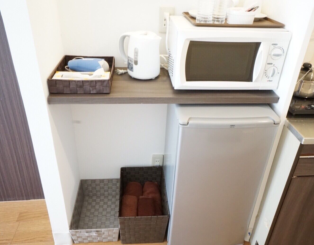 A compact kitchenette with a microwave, kettle, and a small refrigerator.