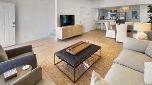 A modern living room with a sofa, a coffee table, and a TV on a wooden cabinet.