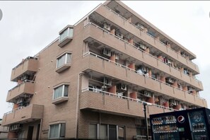 Ein mehrstöckiges Backsteingebäude mit Balkonen, Klimaanlagen und einem Verkaufsautomaten.