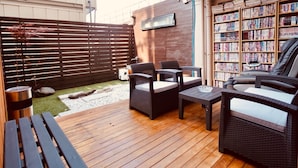 An outdoor patio area with wicker furniture, a small table, and a bookshelf filled with books. - Hostel 758 Nagoya3C (Nagoya)