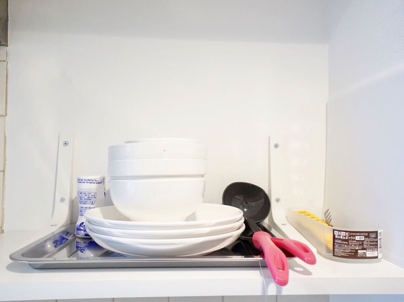 A kitchen counter with stacked white bowls, a black spatula, and a container of yellow food items.