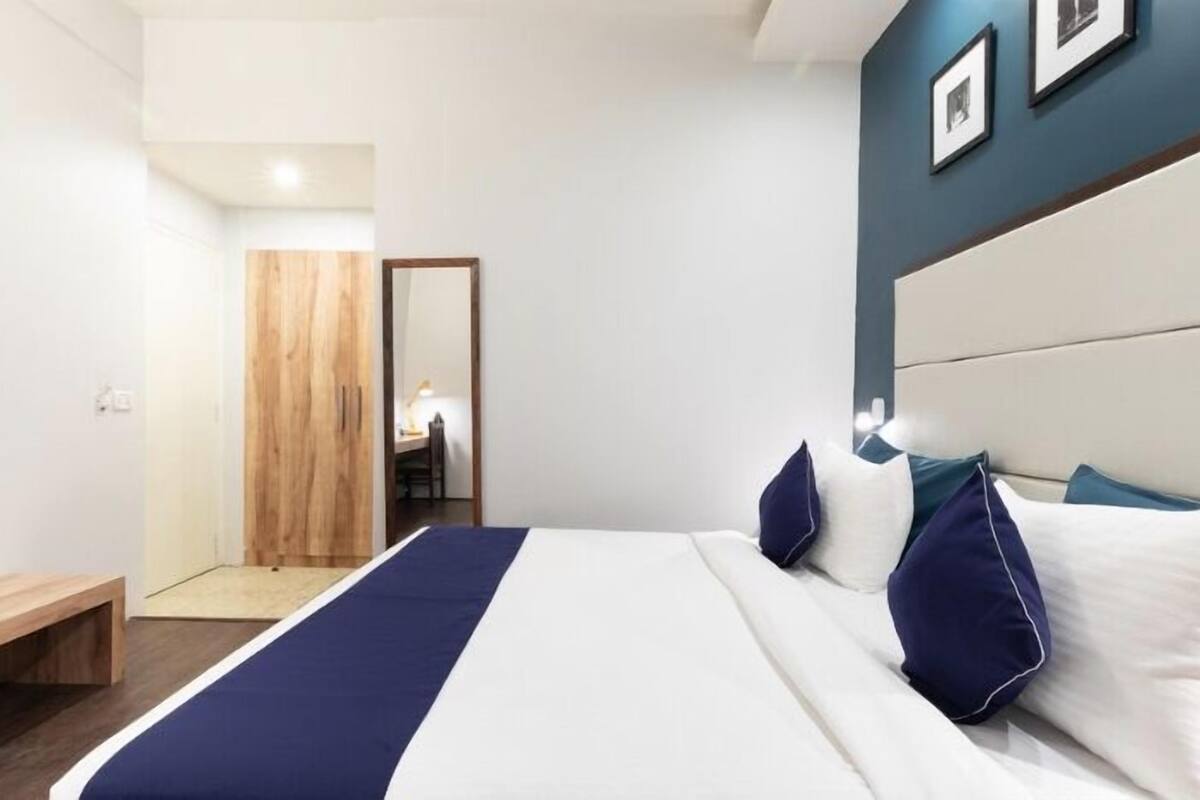 Una habitación de hotel moderna con una cama grande, una puerta de madera y un banco.