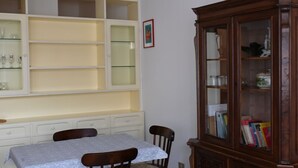 Una stanza con un tavolo da pranzo, sedie, un mobile con ante in vetro e una libreria in legno.