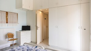 A bedroom with a bed, a chair, a dresser, a television, and white wardrobes. - N164 - Numana, two-room apartment with wonderful sea view (Numana)