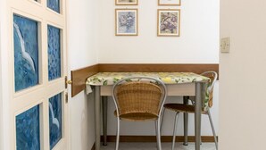 A small dining area with a table and two chairs, a door with glass panels, and framed artwork on the wall. - N164 - Numana, two-room apartment with wonderful sea view (Numana)