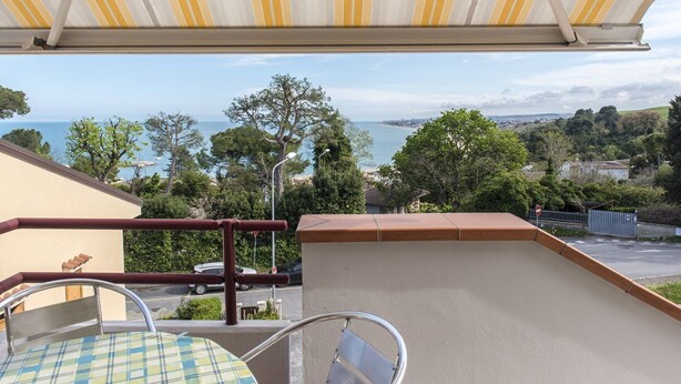 A balcony with a view of the sea, a table with a checkered tablecloth, and a chair. - N164 - Numana, two-room apartment with wonderful sea view (Numana)