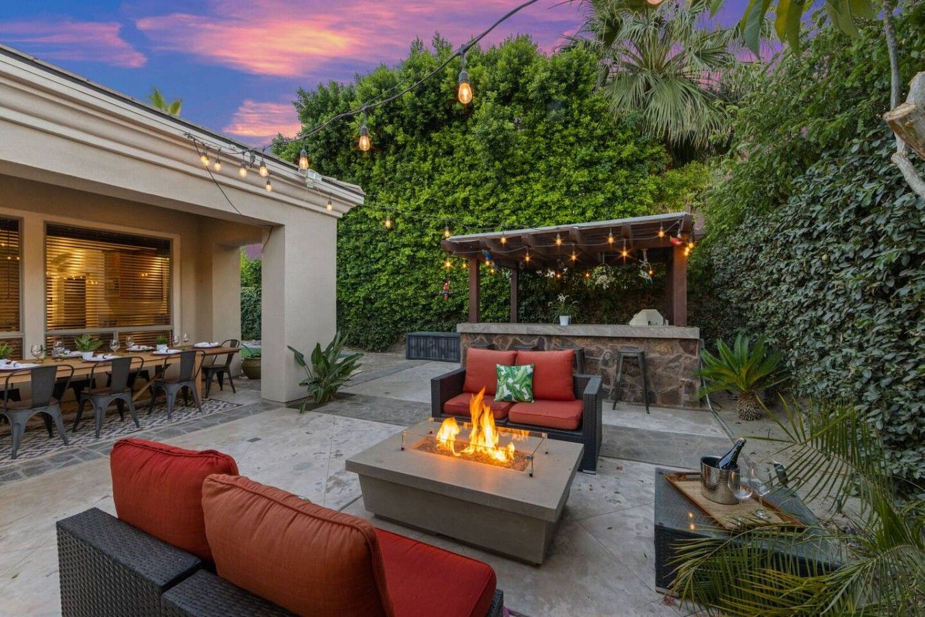 An outdoor patio with a fire pit, seating, and string lights.