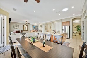 A spacious dining area with a long table, chairs, and a ceiling fan.
