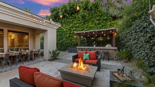 An outdoor patio with a fire pit, seating, and string lights.