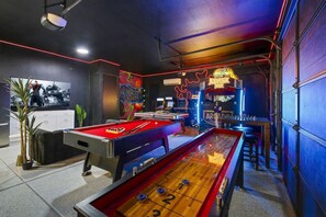 A room with a pool table, foosball table, and arcade machines.