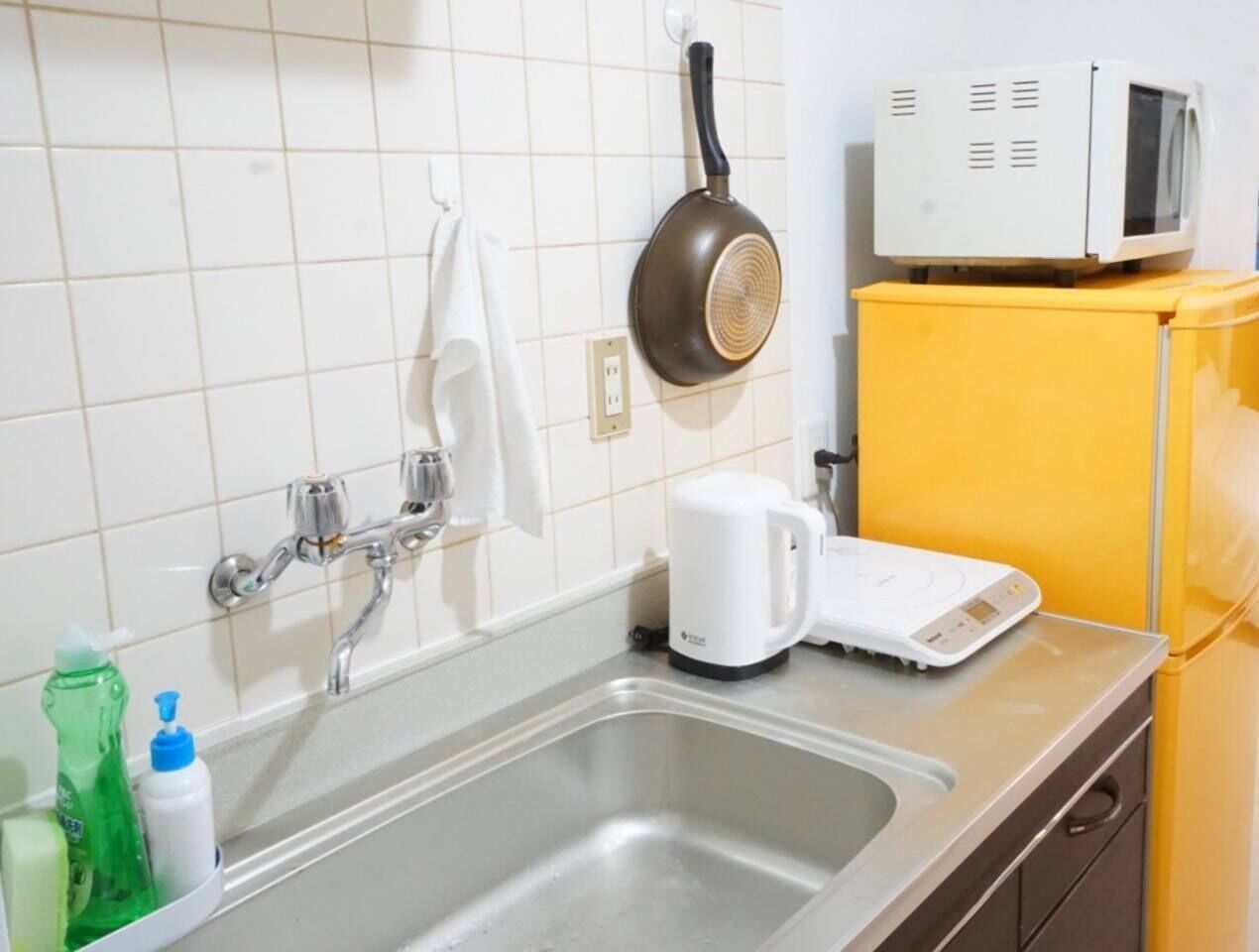 Una cocina con un lavamanos, microondas, cafetera y un refrigerador amarillo.