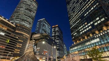 A modern urban skyline with high-rise buildings, including a distinctive curved structure in the foreground.