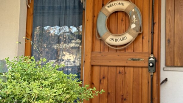 A wooden door with a 'Welcome On Board' sign and a window with a view of snow-covered mountains. - M244 - Marcelli, three-room apartment with terrace 150m from the sea (Marcelli)