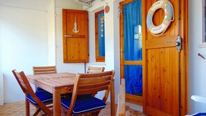 A wooden dining table with chairs, a wooden door with a blue curtain, and a life ring on the door. - M244 - Marcelli, three-room apartment with terrace 150m from the sea (Marcelli)