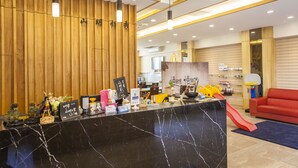 Un área de recepción con mostrador de mármol, paneles de madera y un sofá rojo.