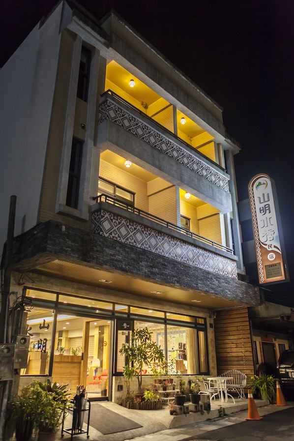 Enter a charming building with a ground-floor entrance and outdoor seating area, featuring a balcony with a railing and decorative tile work.