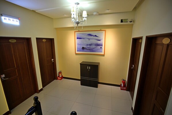 A hotel lobby with wooden doors, a chandelier, a framed painting, and a fire extinguisher. - Shan Ming Shui Xiu B&B (Yuchi)