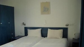 A double bed with two pillows, a nightstand, a wall-mounted light, and a door. - Makrigialos: big family apartment, 2 bedrooms, sea views, WiFi (Makrigialos)