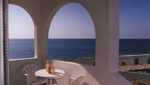 A balcony with two white chairs and a small table, overlooking a beach and the ocean. - Makrigialos: big family apartment, 2 bedrooms, sea views, WiFi (Makrigialos)