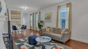 Sala de estar con sofá, mesa de centro y sillas. Una escalera conduce a otro nivel.