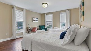 Habitación de hotel con una cama grande, un escritorio, una silla y vistas a la ciudad a través de las ventanas.