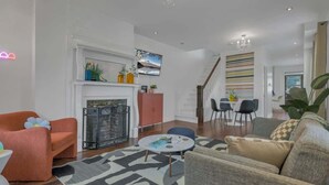 Una sala de estar moderna con chimenea, un comedor y una escalera que conduce a otro nivel.