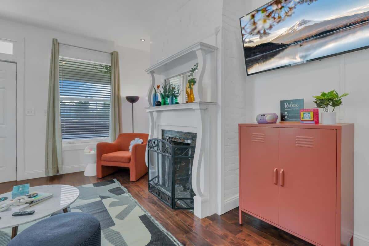 A living room with a fireplace, a television mounted on the wall, and a pink cabinet.