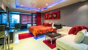 Un dormitorio moderno con una cama grande, un sofá blanco y una pared de acento roja.
