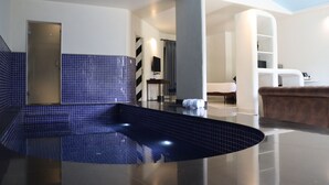 A modern bathroom with a blue-tiled floor, a bathtub, and a shower area.