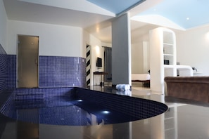 A modern bathroom with a blue-tiled floor, a bathtub, and a shower area.