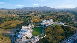 Ein großes, modernes Hotel mit Innenhof, umgeben von üppiger Vegetation und Bergen im Hintergrund.