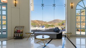 Ein modernes Wohnzimmer mit einer Couch, einem Couchtisch und Blick auf eine Berglandschaft durch große Fenster.