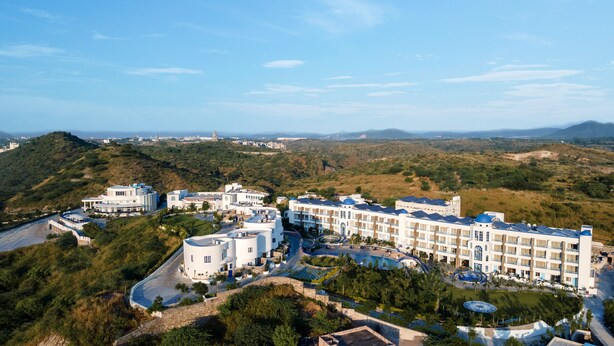 A resort with multiple buildings, a pool, and a view of the surrounding hills.
