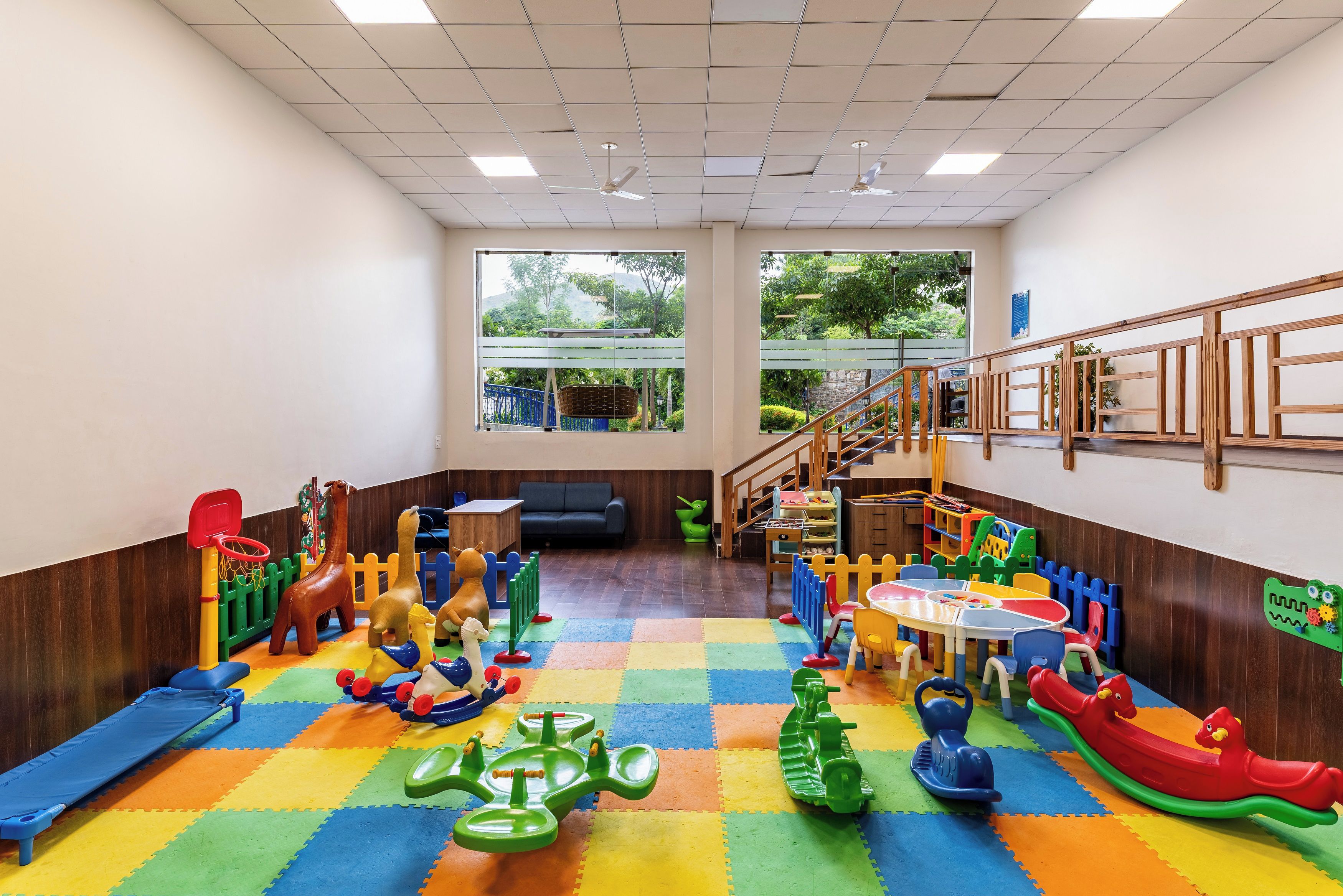 Een kinderspeelkamer met kleurrijk speelgoed, een speeltje en uitzicht op groen.