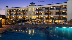 A hotel with a large pool, multiple balconies, and a central tower.