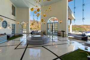 Un vestíbulo amplio con una zona de estar central, ventanas grandes y vistas al exterior.