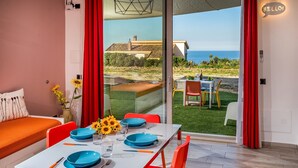 A dining area with a table set for four, red chairs, and a view of the sea through large glass doors. - Apt Mari E Monti A 2 Km Da Riserva Dello Zingaro (Castellammare del Golfo)