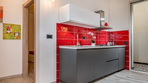 A modern kitchen with a grey countertop, red backsplash, and a white cabinet above. - Apt Mari E Monti A 2 Km Da Riserva Dello Zingaro (Castellammare del Golfo)