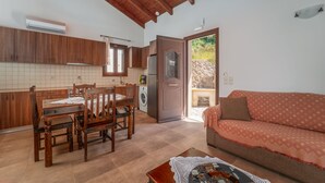 A spacious living area with a wooden dining table and chairs, a sofa, and a kitchen with wooden cabinets and a tiled backsplash. - Kerithra Villa, overlooking Vasiliki bay, close to the beach and other amenities (Lefkada)