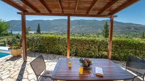 A wooden pergola with a table and chairs, overlooking a mountainous landscape and a body of water. - Kerithra Villa, overlooking Vasiliki bay, close to the beach and other amenities (Lefkada)
