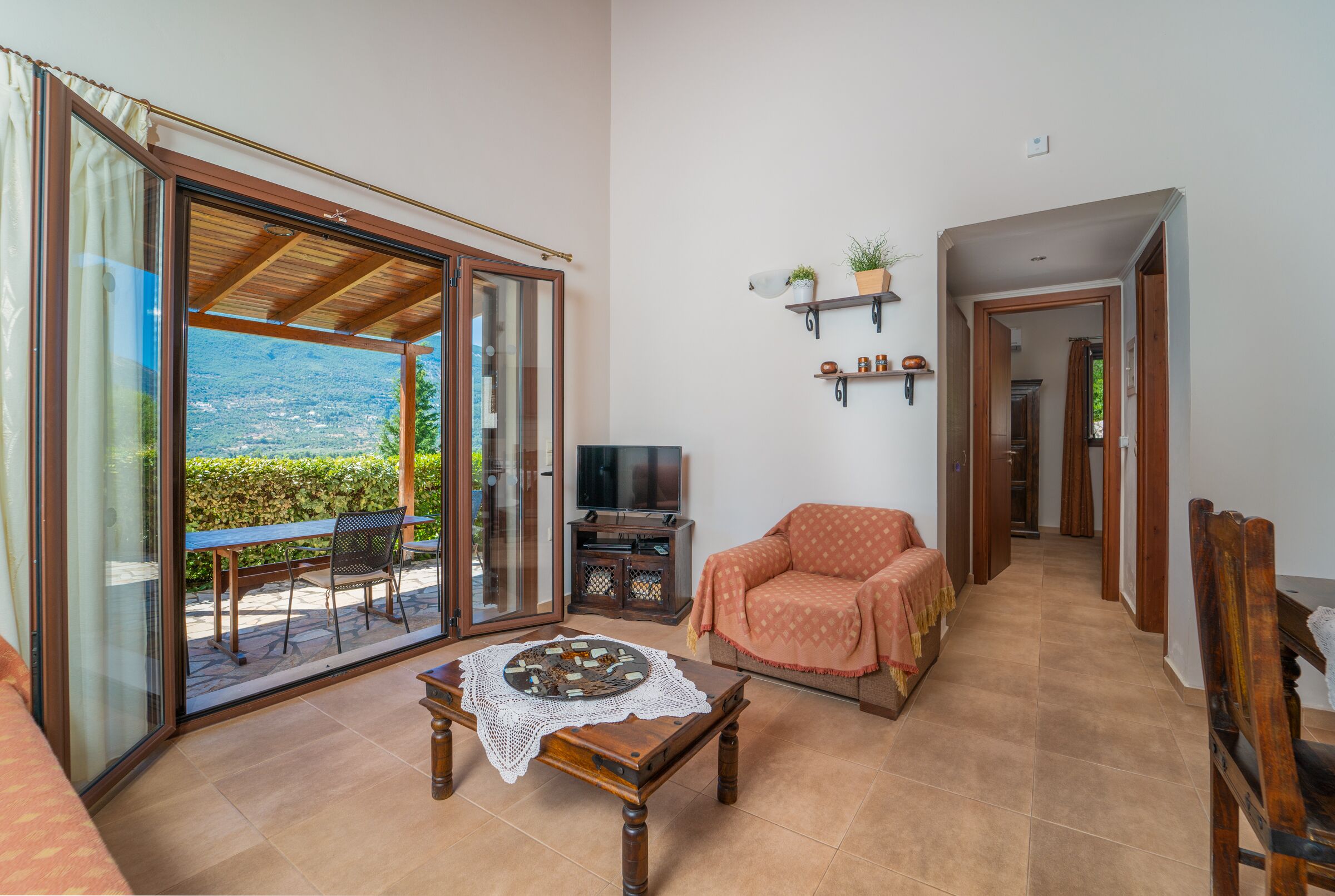 A living room with a sliding glass door leading to a balcony, a television, a sofa, and a coffee table.