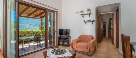 A living room with a sliding glass door leading to a balcony, a television, a sofa, and a coffee table.