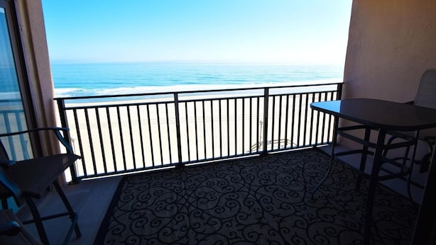 A balcony with a view of the ocean, a table, and two chairs. - Ocean Hideaway (Ocean City)