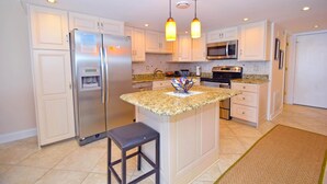 A modern kitchen with white cabinetry, stainless steel appliances, granite countertops, and pendant lighting. - Ocean Hideaway (Ocean City)