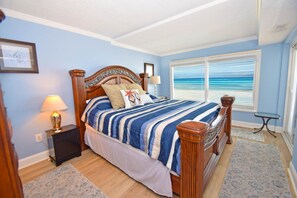 Une chambre à coucher avec un lit, une table de chevet, une lampe, une fenêtre donnant sur un beau paysage et une petite table.