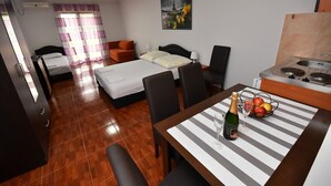 Ein Hotelzimmer mit Bett, einem Esstisch mit Flasche und Gläsern, einer Küchenzeile und einem Badezimmer.